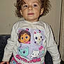 cartoon, cats, child, clothing, couch, curly_hair, drool, expression, face, furniture, hair, indoor, long_sleeve, pajamas, pants, person, shirt, sitting, toddler, wall