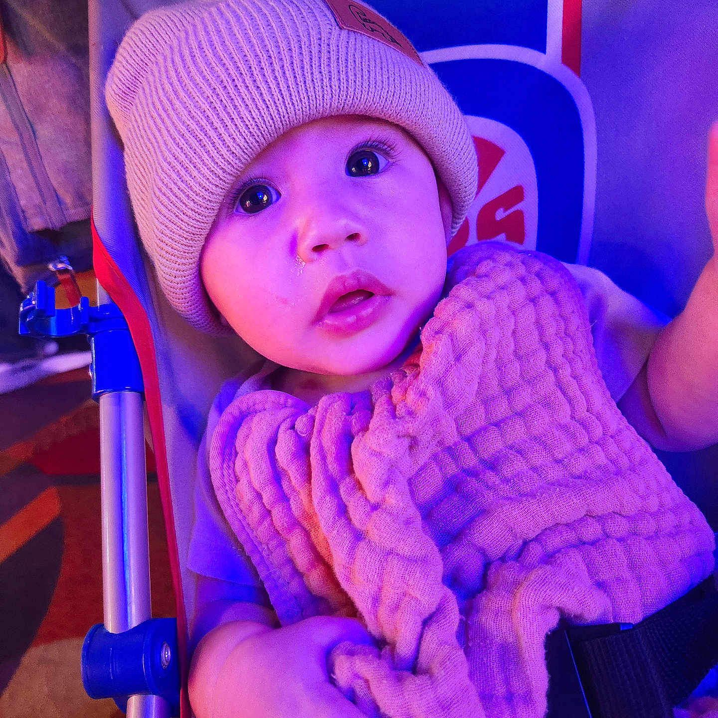 Asher is registered to the contest to win money with this photo: baby, blanket, child, clothing, cozy, curious, cute, eyes, face, hand, hat, indoors, infant, person, purple_light, seat, soft_texture, stroller, warm, young