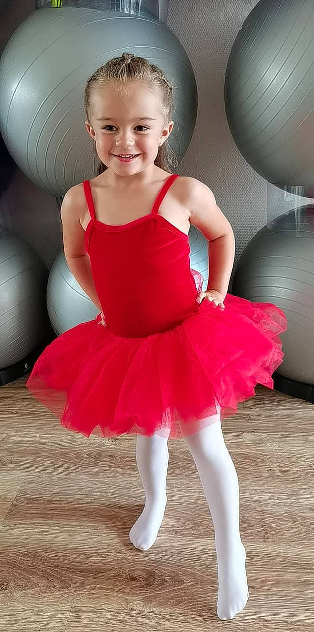 Kélya a rejoint le concours — aidez-le/la à gagner de superbes lots ! baby_toddler_clothing, ballet_tutu, dance, day_dress, dress, face, facial_expression, flash_photography, hair, hairstyle, joy, leg, muscle, one_piece_garment, person, pink, red, shoulder, smile, toddler