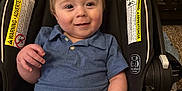 Beau is registered to the contest to win money with this photo: baby, child, smiling, car_seat, blue_shirt, striped_shorts, whale_pattern, toddler, indoor, wooden_dresser, carpet, warning_label, clothing, person, cute, happy, seat, portrait, infant, young_child