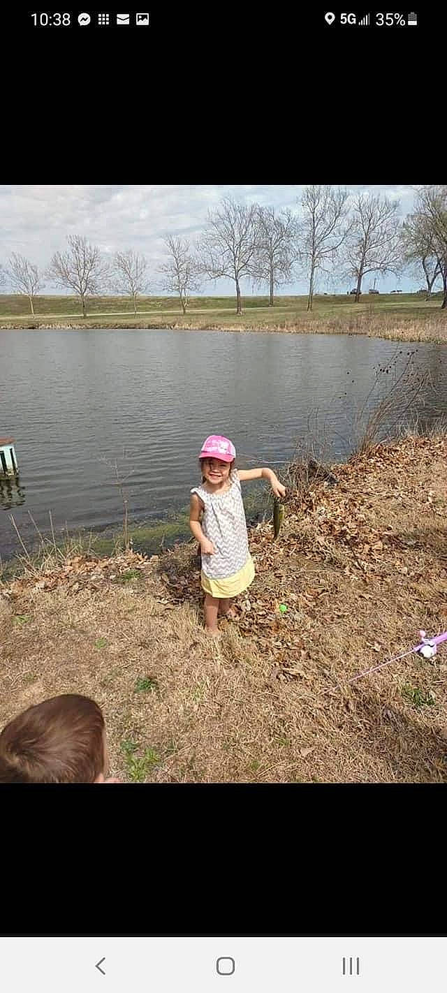 Blaine is registered to the contest to win money with this photo: bank, grass, happy, headwear, joy, lacustrine_plain, lake, landscape, leisure, natural_environment, natural_landscape, people_in_nature, person, plant, recreation, reservoir, sky, tree, water, water_resources