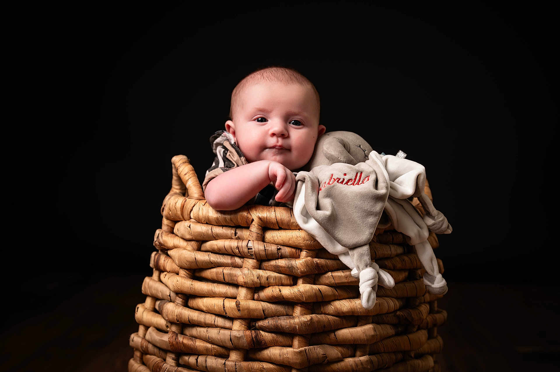 Gabriella joined the competition — help win amazing prizes! baby, basket, plush_toy, child, infant, cute, portrait, soft_toy, woven, hand, expression, indoors, studio, dark_background, face, clothing, resting, newborn, comfort, photography