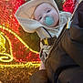 baby, infant, pacifier, hoodie, child, face, person, festive, christmas_lights, holiday, glowing_lights, outdoor, winter_clothing, cozy, cute, holding, red_lights, yellow_lights, decoration, tree