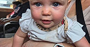Jane is registered to the contest to win money with this photo: baby, child, adult, woman, watch, smartwatch, face, blue_eyes, rosy_cheeks, hand, arm, clothing, sitting, indoor, window, people, transport, seat, candid, portrait