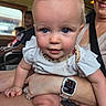 baby, child, adult, woman, watch, smartwatch, face, blue_eyes, rosy_cheeks, hand, arm, clothing, sitting, indoor, window, people, transport, seat, candid, portrait