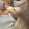child, girl, puppy, dog, cream_colored, fluffy, sofa, couch, blanket, pacifier, portrait, indoor, home, kitchen, cuddling, sitting, brown_hair, profile, cozy, pet