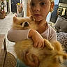 child, cat, orange_cat, fluffy, pet, hugging, indoors, living_room, couch, kitchen, home, portrait, selfie, short_hair, pale_shirt, arms, animal, companion, cozy, domestic