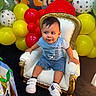 toddler, child, chair, balloons, yellow_balloons, red_balloons, white_balloons, paw_prints, casual_clothing, shorts, sneakers, indoor, party_decoration, happy, portrait, baby, furniture, colorful, cute, smiling