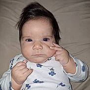 Ayla joined the competition — help win amazing prizes! baby, infant, face, hand, clothing, onesie, blue_flower_pattern, hair, lying_down, skin, cheek, expression, gesture, young_child, cute, portrait, indoor, person, child, closeup