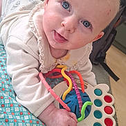 Rose a rejoint le concours — aidez-le/la à gagner de superbes lots ! baby, blanket, blue_eyes, cheek, colorful_toys, cute, drool, floor, hand, infant, onesie, pillow, play, playmat, portrait, smile, sofa, teether, toy, tummy_time