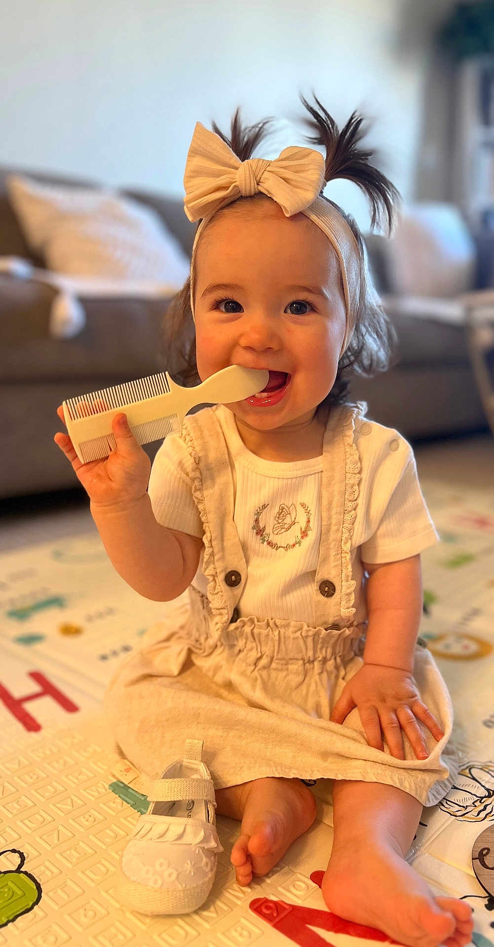 Anastasia is registered to the contest to win money with this photo: toddler, child, baby, sitting, comb, headband, bow, hair, smiling, barefoot, shoe, playmat, indoor, cute, happy, clothing, person, face, hand, living_room