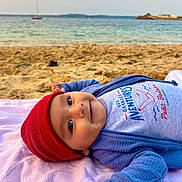Islem a rejoint le concours — aidez-le/la à gagner de superbes lots ! baby, beach, beanie, blanket, boat, child, clothing, eyes, happy, hat, infant, ocean, portrait, red_hat, relaxing, sand, sea, shore, smile, towel