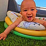 baby, infant, smile, tooth, arm, inflatable_ring, pool_toy, grass, lawn, outdoor, sky, blue_sky, couch, face, close_up, happy, playful, summer, cute, portrait