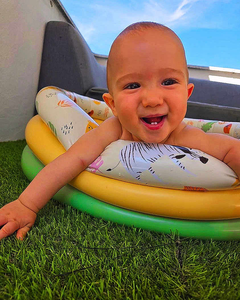 Marius a rejoint le concours — aidez-le/la à gagner de superbes lots ! baby, infant, smile, tooth, arm, inflatable_ring, pool_toy, grass, lawn, outdoor, sky, blue_sky, couch, face, close_up, happy, playful, summer, cute, portrait