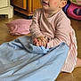 blanket, blue_blanket, cabinet, child, curious, expression, face, floor, furniture, hands, indoor, person, pink_dress, playtime, room, sitting, toddler, toy, wooden_floor, young_child