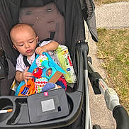 Jasper is registered to the contest to win money with this photo: baby, stroller, toy, wipes, sidewalk, grass, infant, child, outdoor, play, colorful, plastic, person, seat, handlebar, footwear, curious, young, candid, daylight