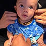 baby, child, infant, blue_onesie, shark_pattern, gold_chain, hands, holding, curious, wide_eyes, cute, indoor, portrait, closeup, skin, human, person, clothing, expression, adorable