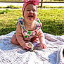 baby, child, smiling, outdoor, grass, blanket, headband, pink_bow, toy, sunlight, happy, cute, infant, sitting, colorful_clothing, nature, portrait, daylight, playful, cheerful