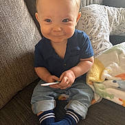 Carter is registered to the contest to win money with this photo: baby, child, smiling, indoor, couch, blanket, blue_shirt, jeans, socks, cute, face, hands, toy, cozy, living_room, portrait, comfort, soft, happy, young