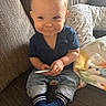baby, child, smiling, indoor, couch, blanket, blue_shirt, jeans, socks, cute, face, hands, toy, cozy, living_room, portrait, comfort, soft, happy, young