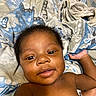 baby, infant, child, portrait, close_up, face, smiling, lying_down, bed, bedding, blanket, bedroom, indoors, hand, eyes, hair, bare_shoulders, relaxed, photography, cute