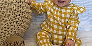 Giada Mae is registered to the contest to win money with this photo: baby, child, smiling, headband, bow, yellow_checkered_outfit, knitted_cushion, wooden_sign, milestone, seven_months, white_blanket, sitting, happy, indoors, cute, portrait, infant, hand, feet, face