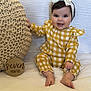 baby, child, smiling, headband, bow, yellow_checkered_outfit, knitted_cushion, wooden_sign, milestone, seven_months, white_blanket, sitting, happy, indoors, cute, portrait, infant, hand, feet, face