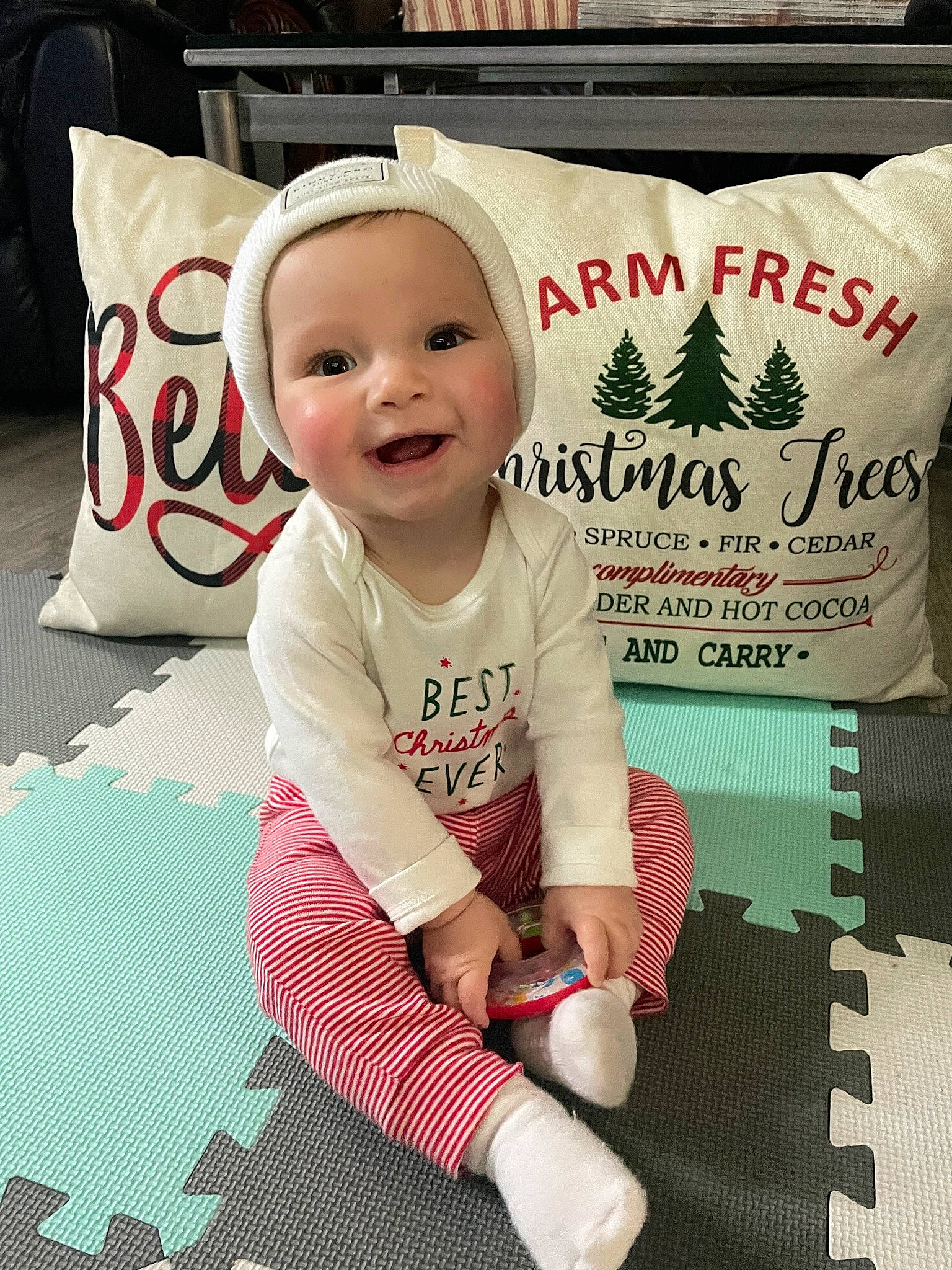 Brody is registered to the contest to win money with this photo: baby, baby_toddler_clothing, carmine, child, christmas_eve, event, flooring, font, happy, headwear, holiday, linens, pattern, person, product, sitting, sleeve, smile, sock, t_shirt