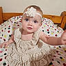 baby, child, girl, headband, flower, dress, polka_dot, blanket, bed, wood, blue_eyes, cute, smiling, indoor, infant, curious, sitting, portrait, person, young
