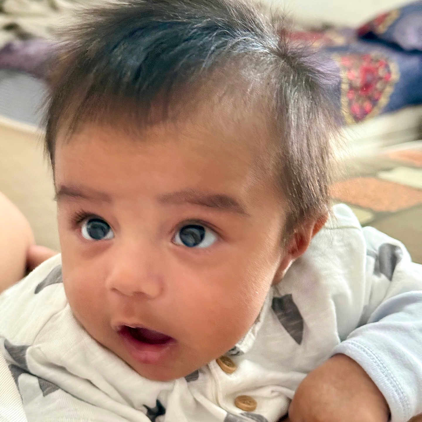 Bijoy is registered to the contest to win money with this photo: baby, button, child, clothing, cozy, cute, expression, face, hair, hand, indoors, infant, looking_up, lying_down, patterned_clothing, person, portrait, skin, soft_focus, young