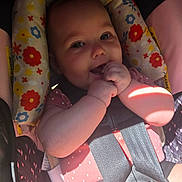 Arabella joined the competition — help win amazing prizes! baby, child, car_seat, seatbelt, infant, hand, face, smiling, pink_clothing, floral_pattern, sunlight, cute, happy, sitting, young_child, closeup, playful, indoors, safety_harness, person