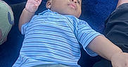 Antoine is registered to the contest to win money with this photo: toddler, child, baby, striped_shirt, shorts, blue_blanket, hand, face, person, legs, pink_socks, casual, indoor, resting, gazing, clothing, toy, relaxed, skin, portrait