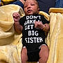 baby, newborn, onesie, text_clothing, blanket, yellow_blanket, infant, lying_down, cozy, soft_texture, socks, cute, sleepwear, person, human, child, baby_clothes, expression, indoor, casual