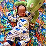 baby, sleeping, pajamas, dinosaur, plush_toy, blanket, colorful, pattern, floor, pacifier, infant, cute, cozy, child, toy, soft, clothing, resting, indoor, headwear