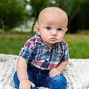 Ryker is registered to the contest to win money with this photo: baby, child, infant, portrait, sitting, outdoor, garden, grass, blanket, plaid_shirt, jeans, bare_feet, blue_eyes, pout, serious_expression, short_hair, face, person, natural_light, photography