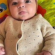 Eline a rejoint le concours — aidez-le/la à gagner de superbes lots ! baby, child, clothing, colorful_background, cute, hand, happy, headband, indoor, infant, knitted_cardigan, laying_down, person, play_mat, pom_pom, portrait, smiling, soft_texture, tongue_out, wide_eyes