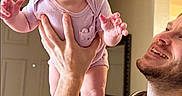Bayleigh is registered to the contest to win money with this photo: arm, baby, beanie, child, expression, family, happy, holding, home, indoor, light, love, man, onesie, person, playful, portrait, skin, smiling, tongue_out