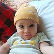 Bayleigh joined the competition — help win amazing prizes! baby, black, blanket, checkered, child, cute, eyes, face, flower_pattern, hat, indoors, infant, lying_down, portrait, red, shirt, smiling, soft, stars, yellow