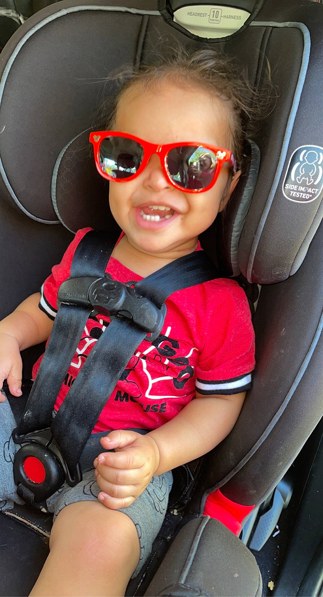 Taylen is registered to the contest to win money with this photo: automotive_design, automotive_lighting, baby_toddler_clothing, cool, eye, eyewear, facial_expression, glasses, goggles, head, joy, lip, person, product, red, skin, sleeve, smile, steering_wheel, sunglasses