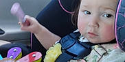 Liliana joined the competition — help win amazing prizes! baby, car_interior, car_seat, child, clothing, expression, face, flower_toy, hair, hand, person, pink_trim, safety, seatbelt, sitting, toddler, toy, window, wooden_toy, young_child