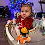 activity_center, baby, child, childhood, christmas_tree, cute, decorations, festive, floor, happy, holiday, home, indoor, infant, person, pigtails, playtime, red_clothing, smiling, toys