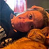 person, cat, orange_tabby, indoor, cozy, relaxed, smiling, face, pet, sleeping_cat, closeup, warm_light, casual, portrait, human, animal, comfort, resting, cuddle, home