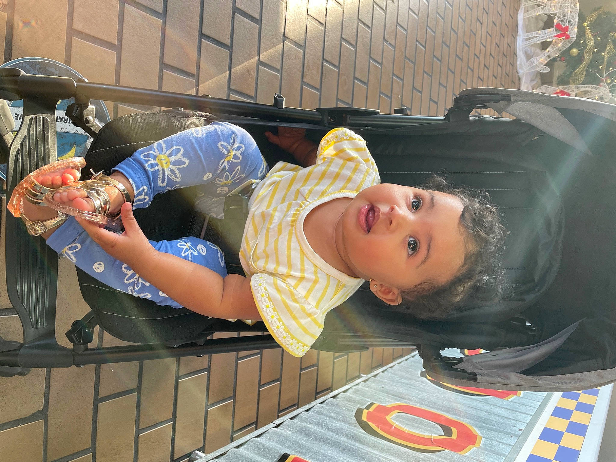Kaelani is registered to the contest to win money with this photo: automotive_design, automotive_tire, child, eyewear, fence, flooring, fun, human_leg, leg, leisure, person, recreation, sandal, shorts, sitting, street_fashion, sunglasses, t_shirt, thigh, tire