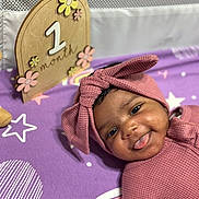 Pync is registered to the contest to win money with this photo: baby, bed, cap, clothing, crib, face, furniture, happy, hat, head, homedecor, indoors, infantbed, person, photography, portrait, purple, quilt, smile, text