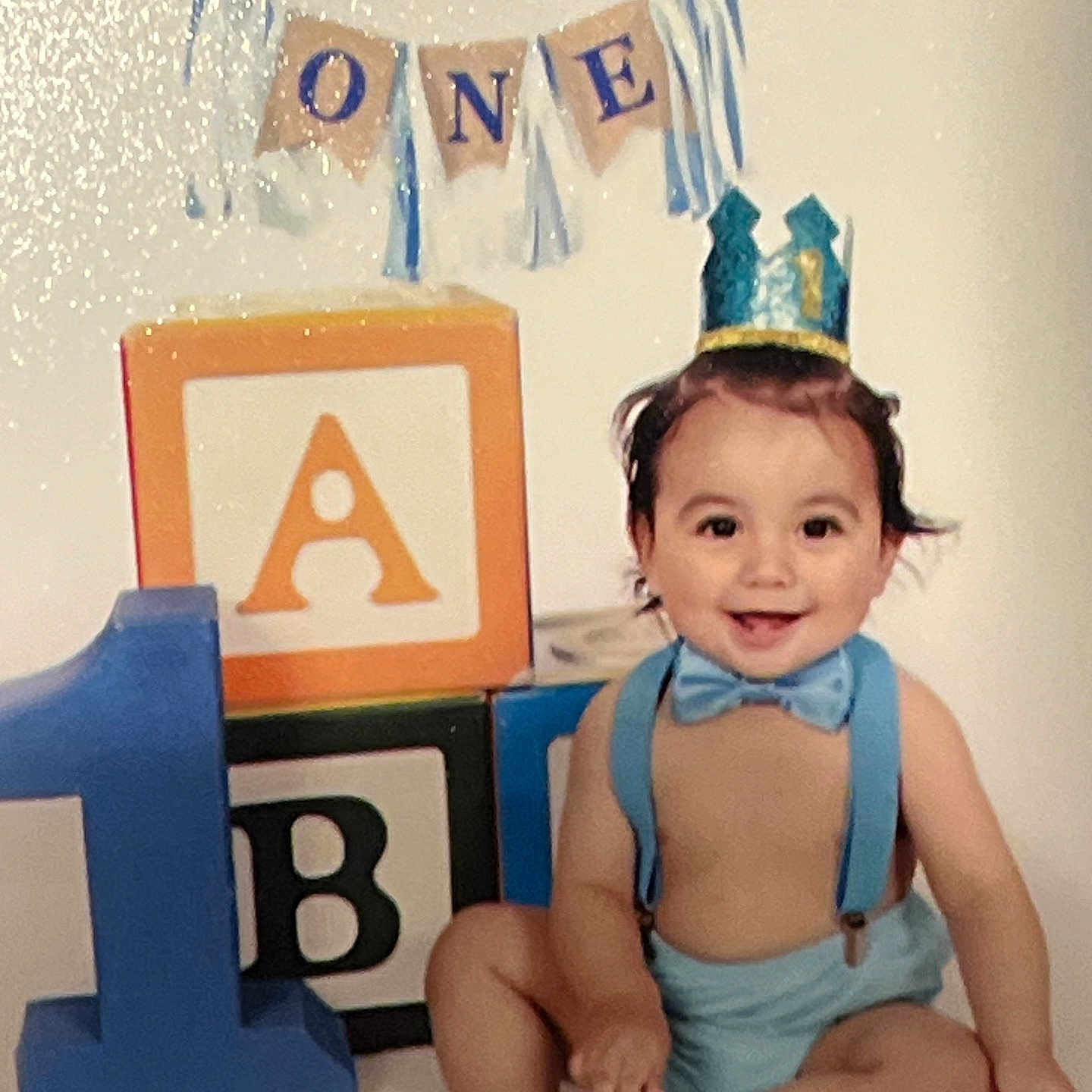 Santos joined the competition — help win amazing prizes! accessories, baby, birthdaycake, cake, clothing, costume, cream, crown, dessert, diaper, face, food, hat, head, indoors, partyhat, person, photography, portrait, text