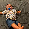baby, barefoot, bedspread, blue, child, cute, gray, indoor, infant, laying_down, orange, pacifier, patterned_clothing, person, relaxed, shirt, shorts, sleepy, toddler, young