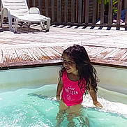 Luna a rejoint le concours — aidez-le/la à gagner de superbes lots ! child, girl, swimming_pool, water, swimsuit, pink, smiling, wet_hair, outdoor, sunny, deck, wooden_deck, lounge_chair, relaxation, summer, vacation, happy, leisure, playful, sunlight