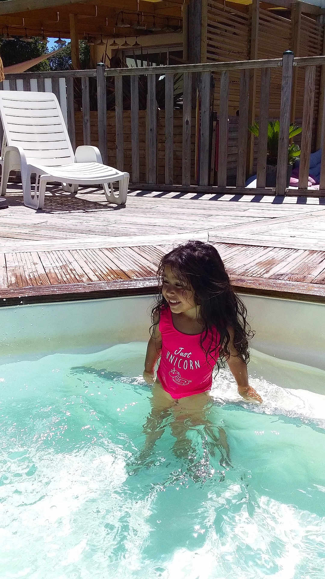 Luna a rejoint le concours — aidez-le/la à gagner de superbes lots ! child, girl, swimming_pool, water, swimsuit, pink, smiling, wet_hair, outdoor, sunny, deck, wooden_deck, lounge_chair, relaxation, summer, vacation, happy, leisure, playful, sunlight