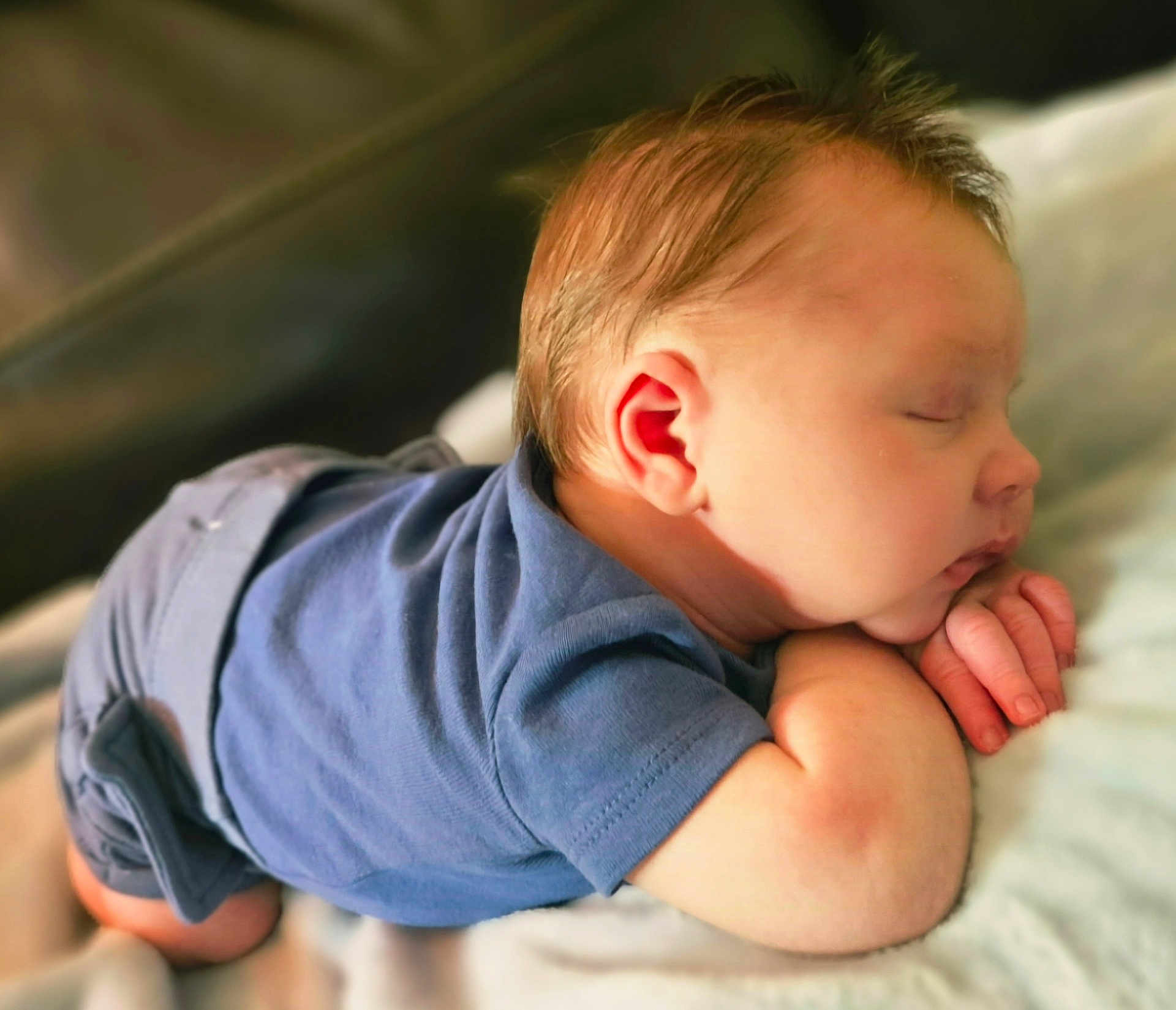 Roman is registered to the contest to win money with this photo: baby, sleeping, blue_clothing, infant, peaceful, cute, tummy, hands, face, skin, hair, closeup, soft, rest, child, newborn, portrait, indoors, comfort, relaxation