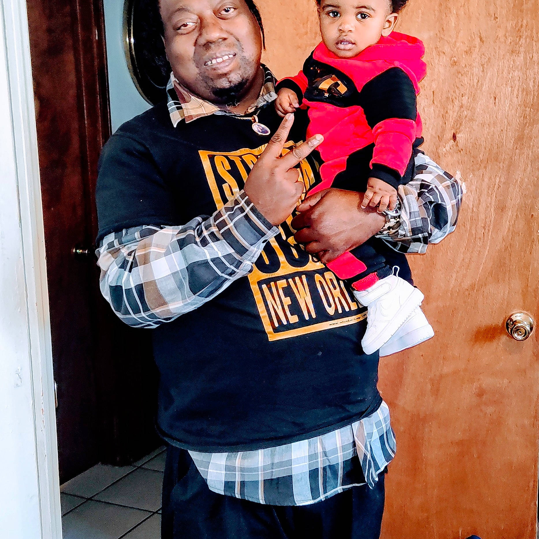 Jalen is registered to the contest to win money with this photo: beard, belt, event, gesture, glove, happy, headwear, jersey, orange, pattern, person, personal_protective_equipment, photograph, plaid, red, sleeve, snapshot, sports_gear, street_fashion, t_shirt